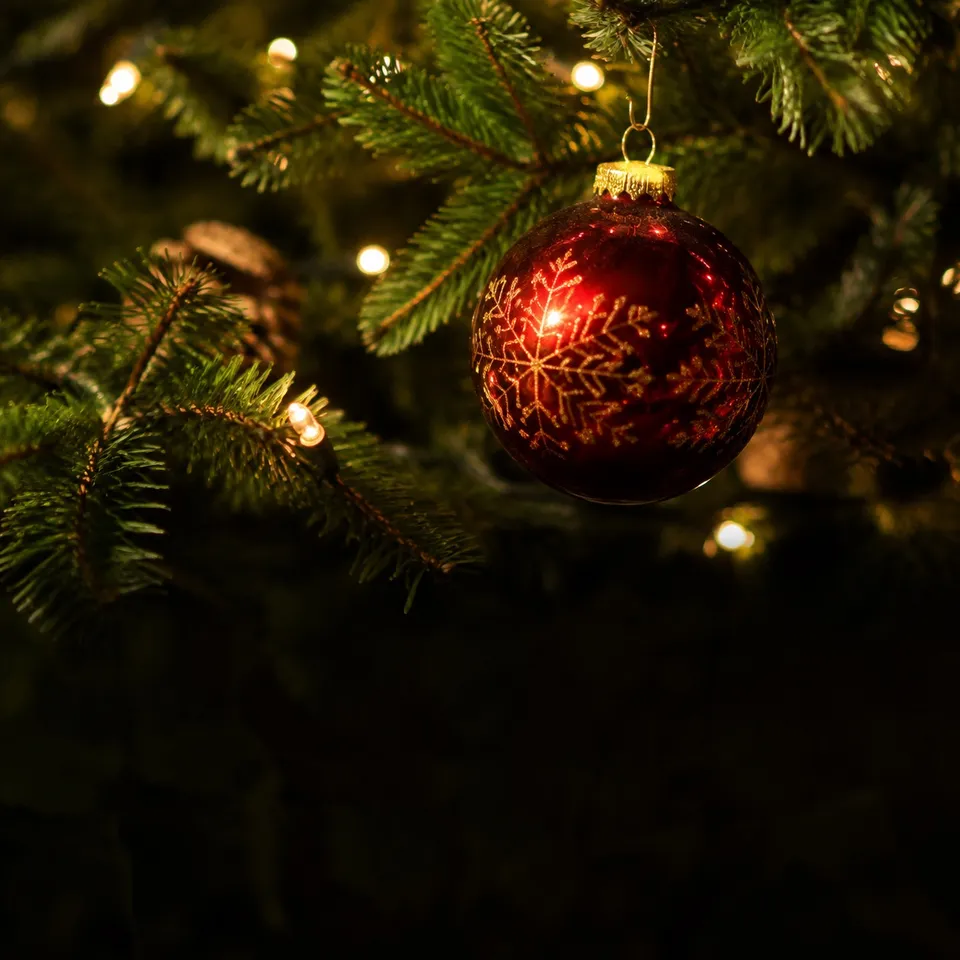 A red ornament and warm Christmas lights